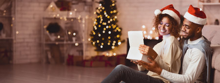 Happy afro couple opening Christmas gift boxの写真素材