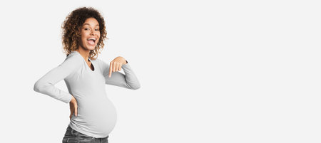 Overjoyed black pregnant woman pointing at her belly