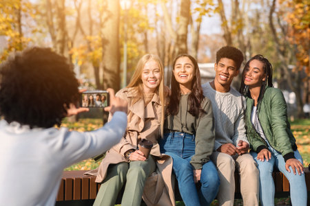 Black teenager taking photo of his international friendsの写真素材