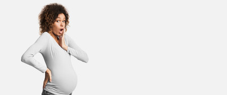 Shocked african-american pregnant lady posing in studioの写真素材