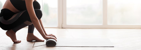 Cropped image of girl rolling yoga mat after exercisingの写真素材