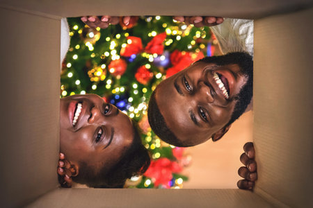 Excited afro couple opening Christmas present at home
