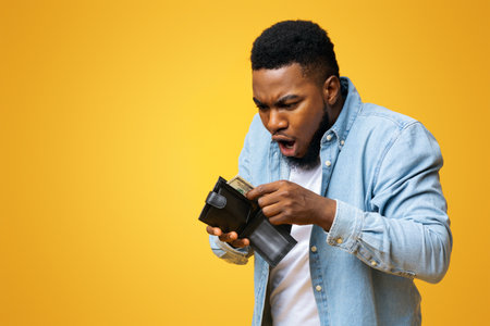 Shocked african american guy holding wallet with dollar cash