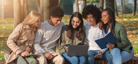 Multiracial friends working on educational project while resting in park
