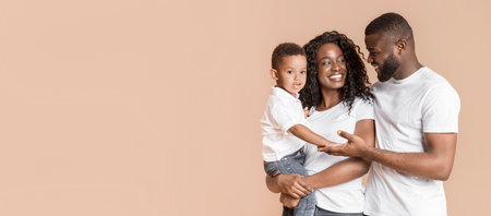 Portrait of loving parents with little son over yellow backgroundの写真素材