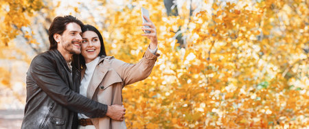 Cheerful young embraced couple taking selfie outdoors