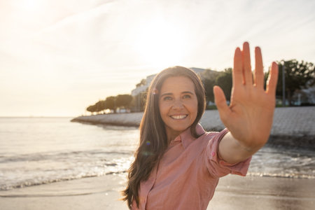 Joyful woman greets sunrise on beach during a calm morning