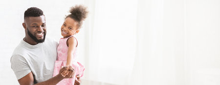 Father and Daughter Enjoying Joyful Dance Together in Bright Roomの写真素材