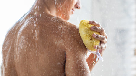 Young man washing his body with sponge