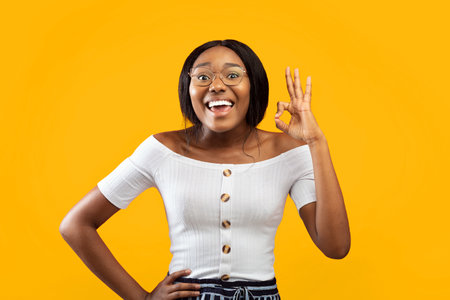 Joyful Afro Girl Gesturing Okay Smiling Standing In Studioの写真素材