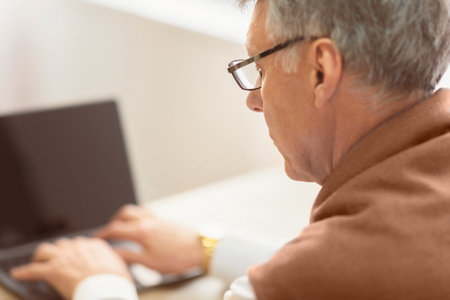 Unrecognizable Elderly Man Using Laptop Sitting Indoor