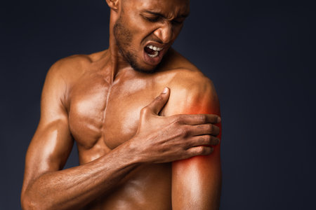 Handsome shirtless black man suffering from pain in armの写真素材