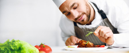 Chef Man In Uniform Decorating Dish In Restaurant Kitchen