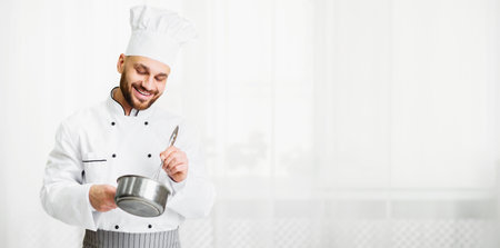 Chef Using Whisk Mixing Ingredients In Saucepan Standing In Kitchenの写真素材