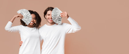 Happy young interracial couple covering eyes with dollar cash