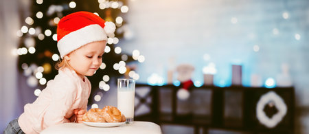 Cute little girl looking at treats for Santa near Christmas treeの写真素材