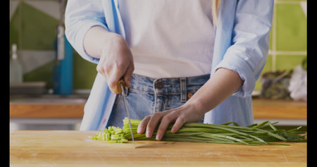 Woman grinding fresh green onions on cutting boardの写真素材