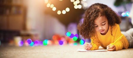 Thoughtful african little girl writing letter to Santa near Xmas treeの写真素材