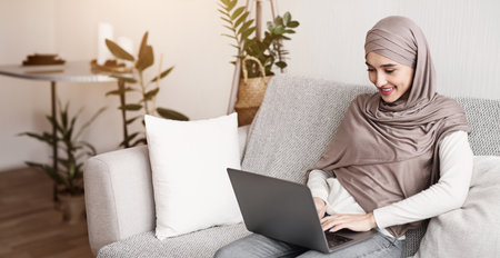 Young muslim woman in hijab using laptop computer at homeの写真素材