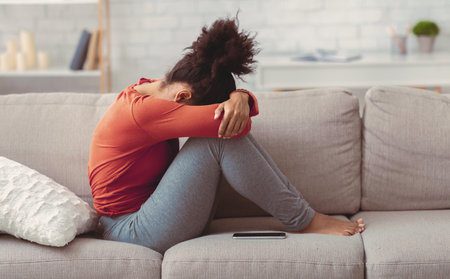 Depressed Woman Burying Face In Hands Sitting On Sofa Indoorの写真素材
