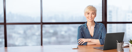 Successful Businesswoman At Laptop Smiling Sitting In Modern Officeの写真素材