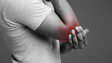 Cropped of afro man rubbing his injured elbowの写真素材