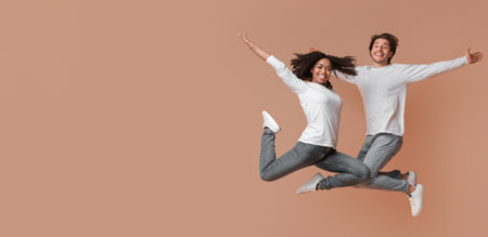 Carefree interracial couple jumping in the air with spreaded arms