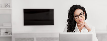Satisfied hispanic girl manager looking at laptopの写真素材
