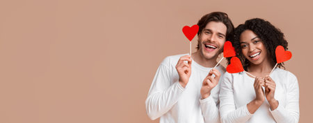 Portrait of romantic multiracial couple holding red paper hearts on sticksの写真素材