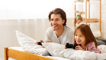 Cheerful family father and daughter playing videogame at home