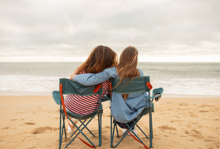 Two friends share a moment on a beach during a cloudy afternoonの写真素材