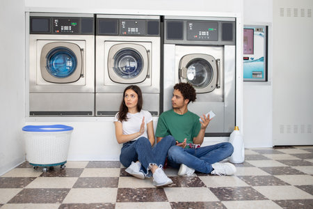 Couple sitting on the floor of a laundromat while waiting for laundry to finish