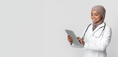 Portrait of smiling afro female doctor in hijab using digital tabletの写真素材