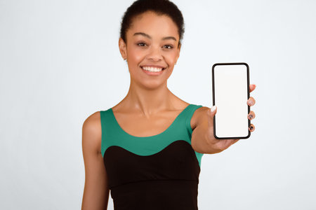 Fit Black Girl Showing Phone Blank Screen Standing, Yellow Backgroundの写真素材