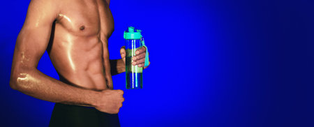 Black Fitness Guy Holding Bottle On Blue Studio Background, Cropped
