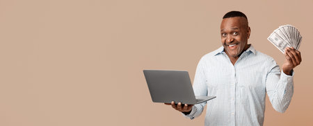 Excited mature african man holding lots of money and laptopの写真素材