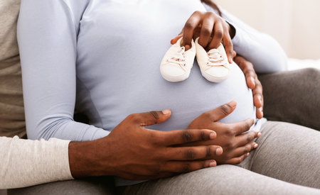 Close up of pregnant woman belly with baby shoes on