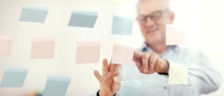 Elderly manager putting sticky notes on window