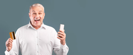 Happy mature man holding credit card and cellphone