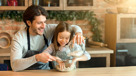 Millennial father and little daughter preparing dough for pie in kitchen togetherの写真素材