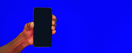 Hand Holding Phone With Blank Screen Over Blue Background, Panoramaの写真素材