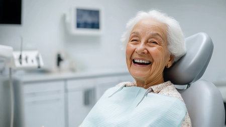 An elderly woman smiles broadly while sitting in a dental chairの素材
