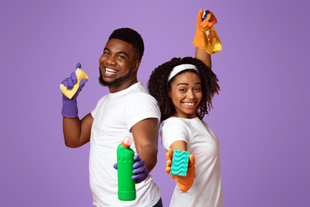Joyful Spring-Cleaning. Cheerful Black Couple Posing With Sponges And Detergents