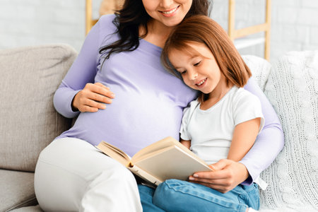 Close up of expecting woman reading to little daughterの写真素材
