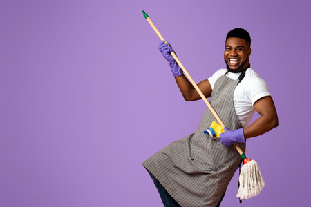 Portrait Of Funny Black Man In Apron With Mop In Handsの写真素材
