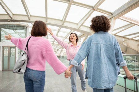 Three friends joyfully greeting each other at a modern indoor venueの写真素材