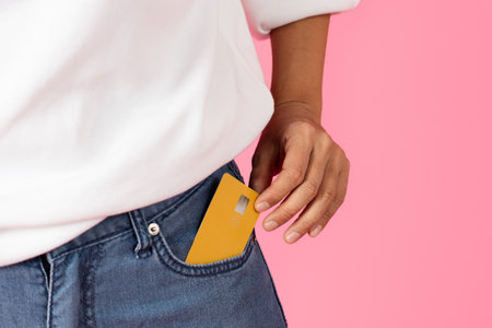 Yellow card in denim jeans pocket on a pink backgroundの写真素材