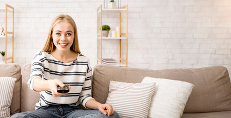 Young attractive woman watching TV at homeの写真素材