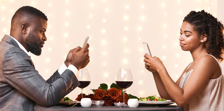 Young couple using mobile phones while date at restaurantの写真素材