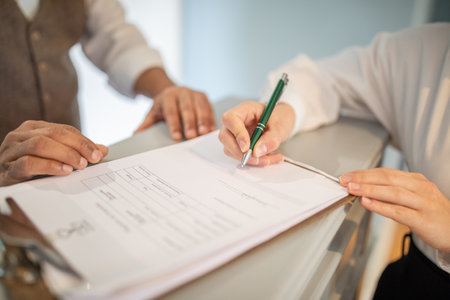 A person signs a document with a green penの写真素材